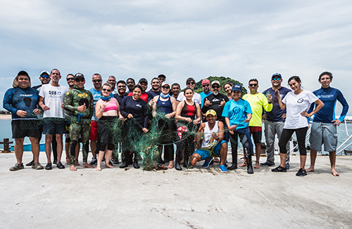 large group of people pose for photo on a beach.