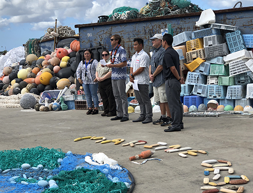 Speakers address a group with marine debris display.