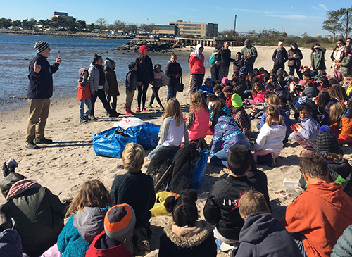 Group of adults and children gathered on a beach.