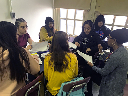 Group of students sitting at a table, working together.