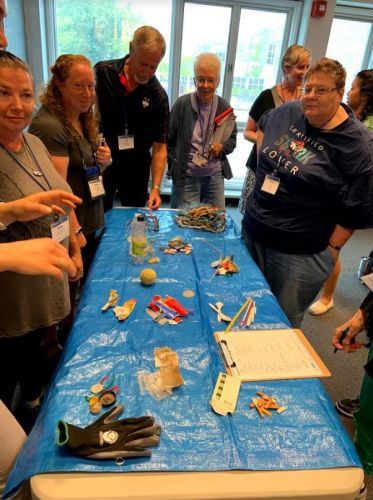 Group of people standing around a table with samples of marine debris.