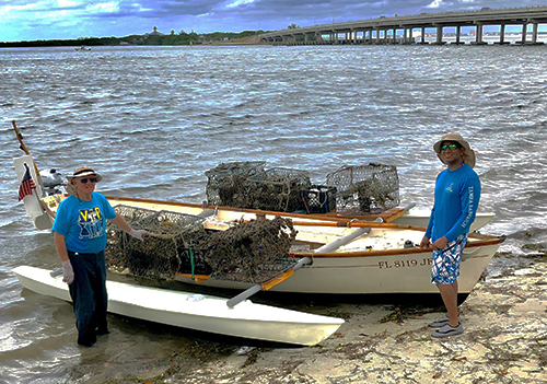 Two people on a beach next to boats.