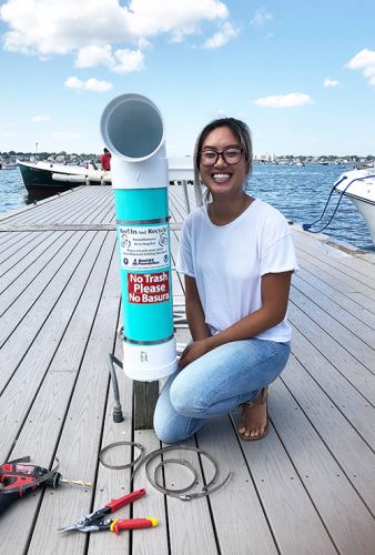 Woman posing next to a "bin" on a pier.