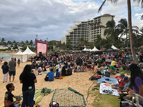 Crowd all watching something outdoors.