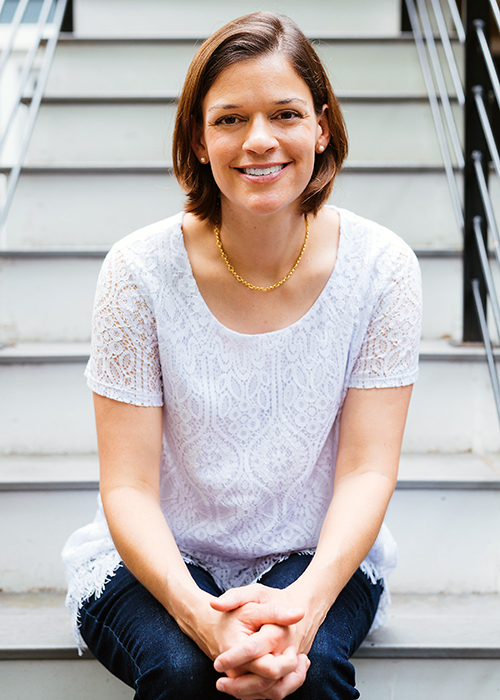 A woman posing for photo while sitting on stairs.