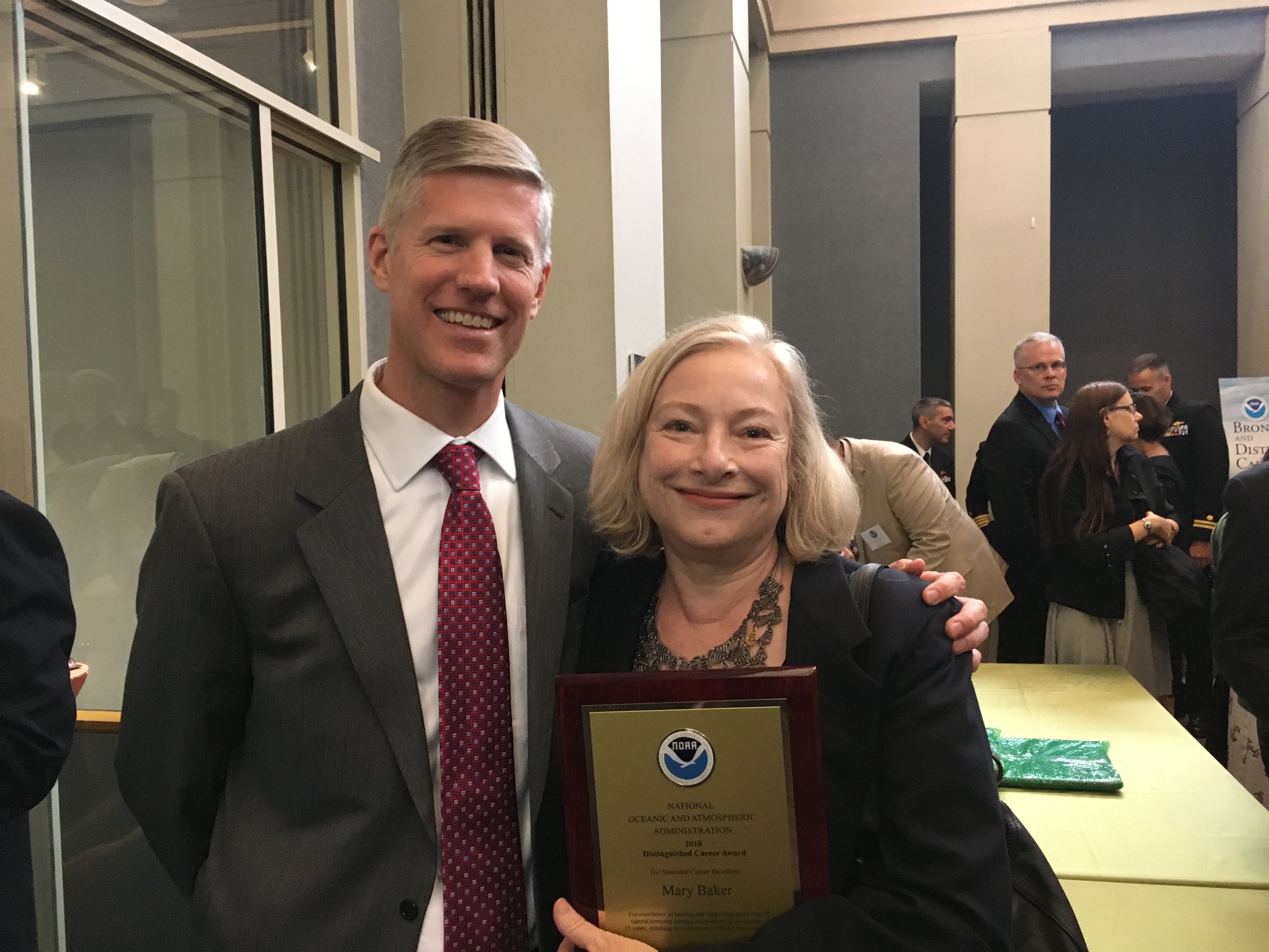 Two people pose for a photo with a plaque. 