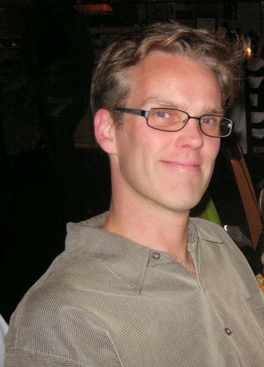 Man in a tan shirt posing for photo.