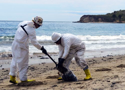 Two cleanup crew members gathering spilled oil on Refugio State Beach, California in 2015. 