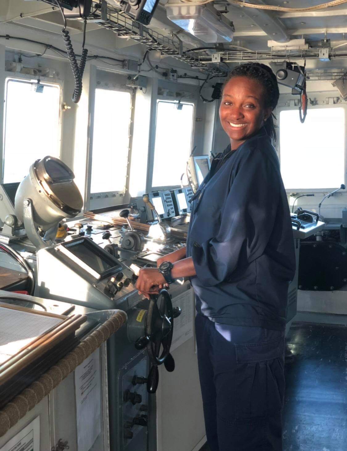 Woman standing in the wheelhouse of a vessel. 