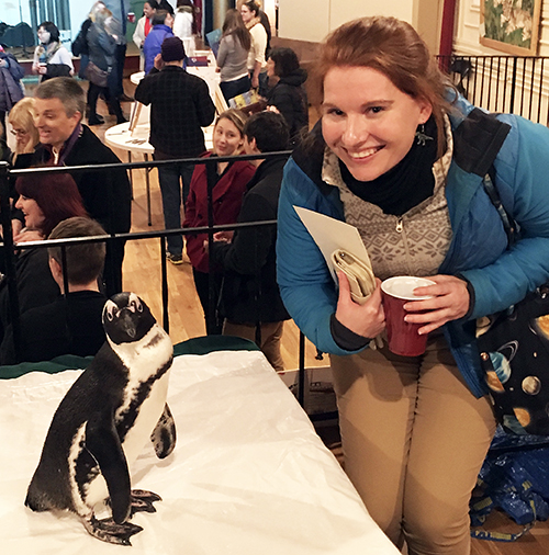 Woman posing with a penguin.