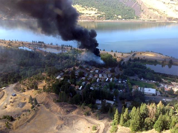 Aerial view of black smoke coming from near a body of water. 