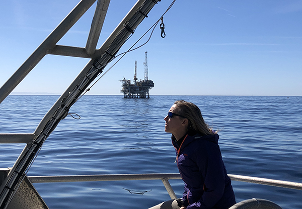 Woman in a boat with oil well in background. 