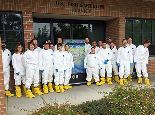 Group in white Hazmat suits posing for photo.