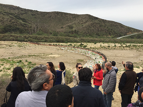 Group of people in front of stark landscape with trash.