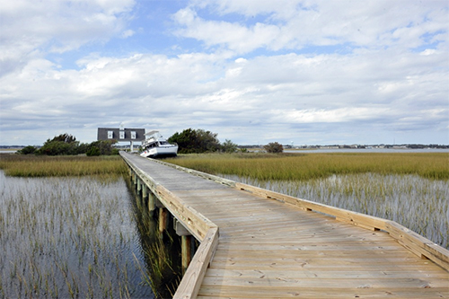 Bridge over water leading to a house and grounded boat. 