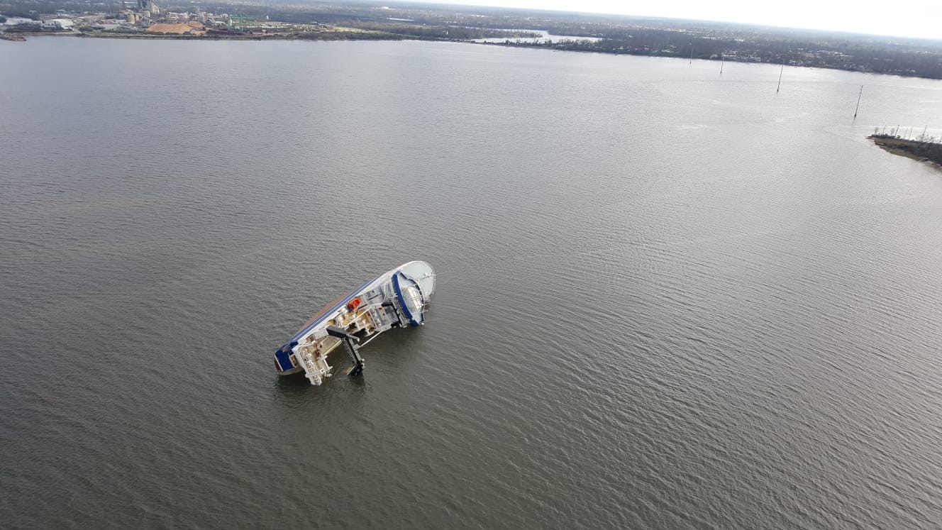 An aerial view of a vessel on its side in a body of water.