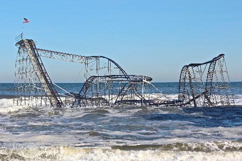 A damaged roller coaster surrounded by water.