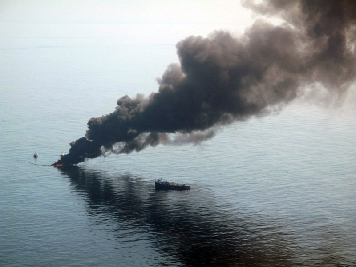 Smoke rising from large body of water.