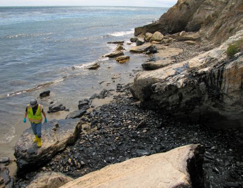 Cleanup worker and oiled boulders on Refugio State Beach where the oil from the pipeline entered the beach. Image: NOAA.