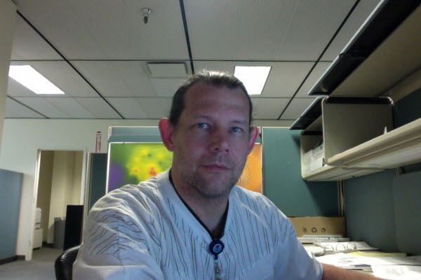 Headshot of a man at a desk.