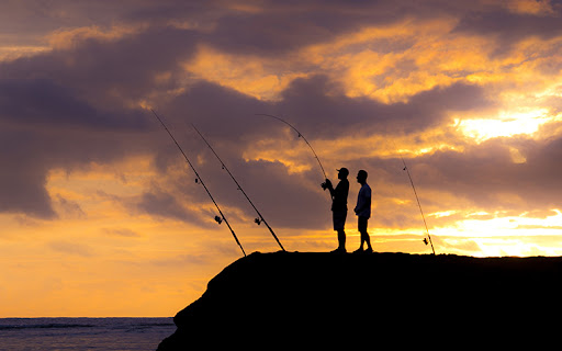 Two people with fishing poles on a shoreline.