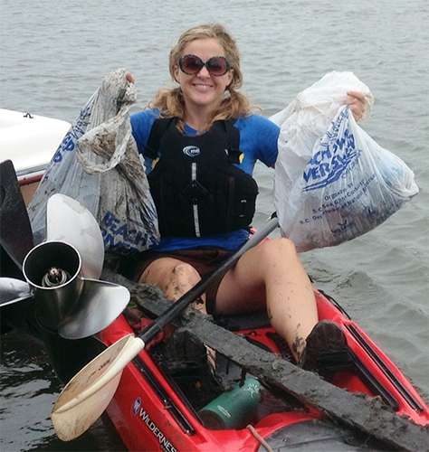 Woman on a boat with bags of debris.