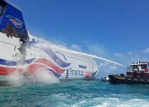 Large vessel with smaller boat spraying water on it.