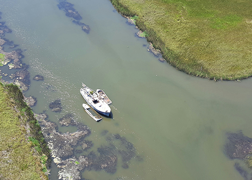 Aerial view of a vessel in a creek surrounded by marsh.