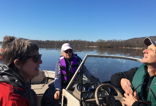 Three people in a boat on a river. 