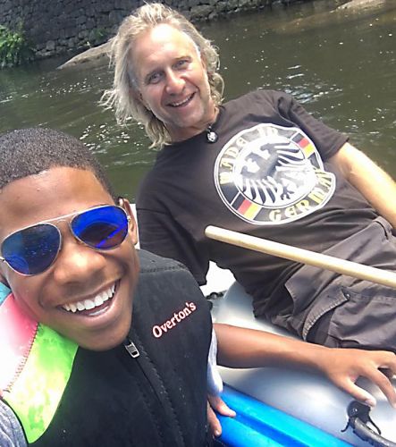 A young boy and a man sitting in a boat at water's edge. 