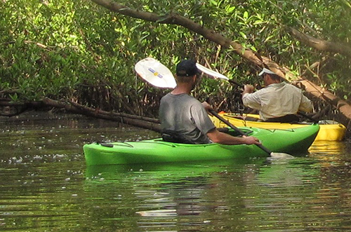 Two men in kayaks in water.