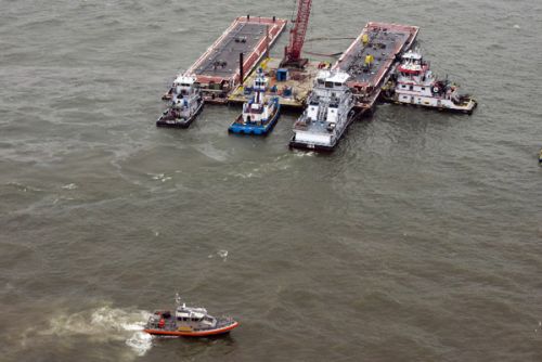 Photo of tugs and barge in water.