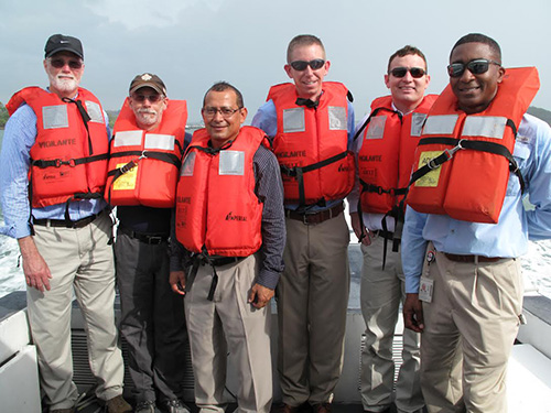 Group of men in life vests pose for photo outdoors. 