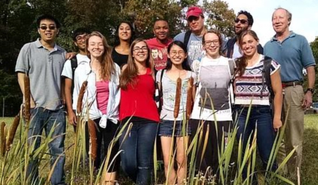 A group of people posing in front of cattails.