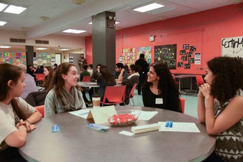 Students talking with a woman at a table. 