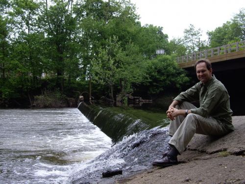 A man sitting next to a dam on a river.