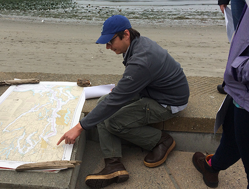 Man looking at nautical chart on a beach.
