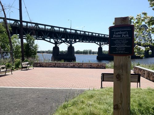 Park entrance sign in foreground, with bridge in background.