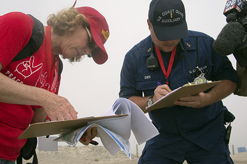 Photo of two people reviewing paperwork on the beach.