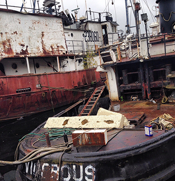 Two rusted and abandoned-looking boats at dock.