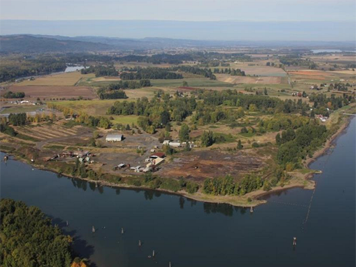 Aerial view of dirt fields and buildings along a river bend.