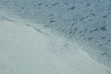 Patches of newly formed ice are visible in the open water of the Chukchi sea.