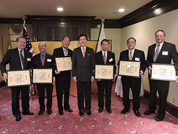 Group of men in suits holding award certificates.
