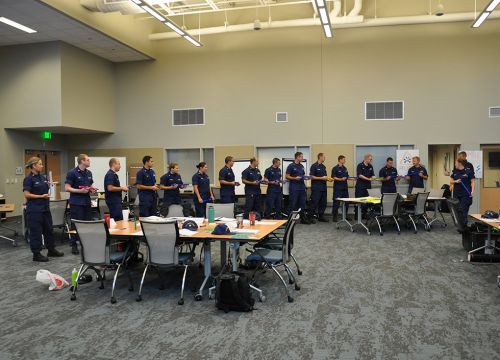 Coast Guard members standing in a line in a conference room.