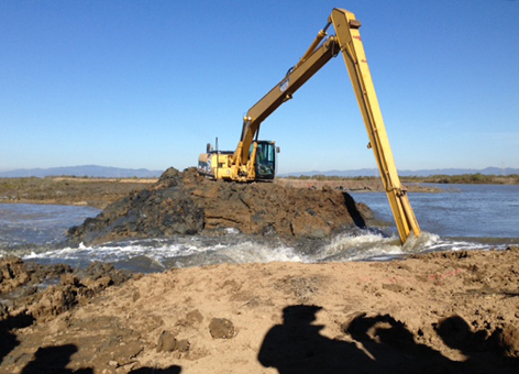 Excavator removing earth to allow tide waters into the recovering wetland.