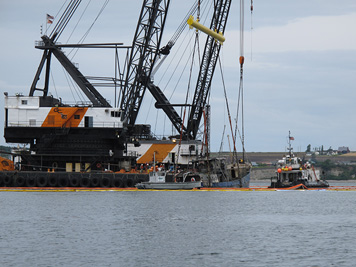 Heavy machinery is brought in to raise a sunken vessel from the sea floor. 