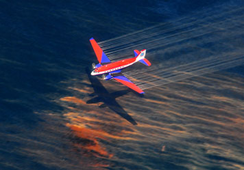 Photo: Aircraft releasing dispersant over water.