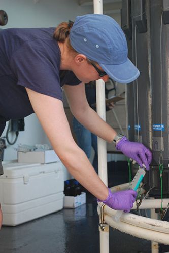 Woman checks for bubbles in a sample of water on board the NOAA Ship Pisces.