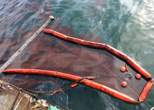 Close up of skimming device on side of a boat with oil and boom.