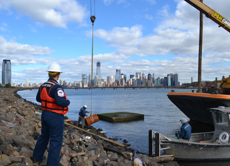 U.S. Coast Guard oversees the removal of a drum with unknown contents.